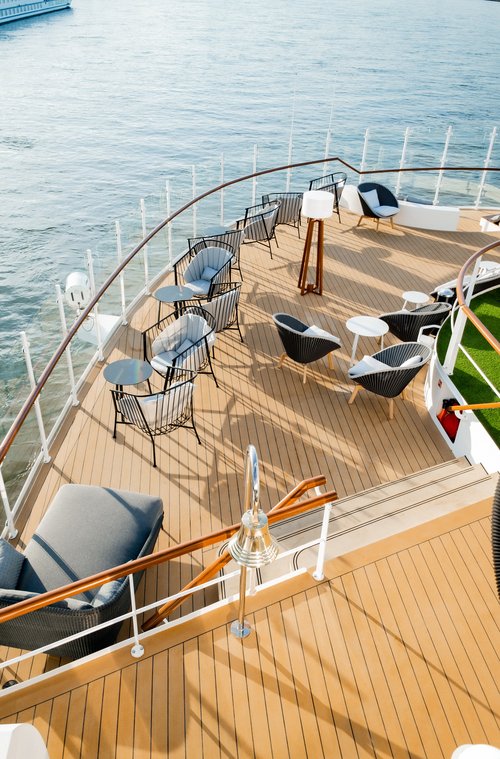 Sitzbereich mit Stühlen und kleinen Tischen auf dem Sonnendeck der A-ROSA SENA mit Blick auf das Wasser