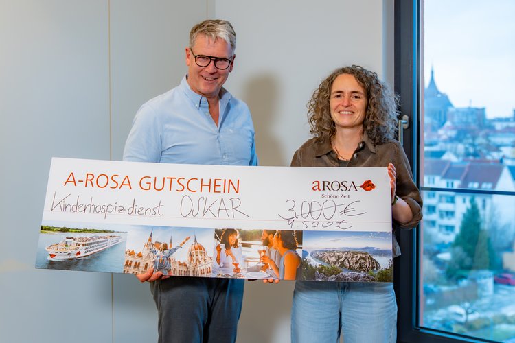 Zwei Personen, unter anderem A-ROSA CEO Rolf-Dieter Maltzahn, halten einen großen Gutschein mit der Aufschrift 'A-ROSA GUTSCHEIN' und dem Betrag '4.500 €' in den Händen.