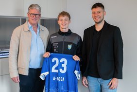 Rolf-Dieter Maltzahn links neben zwei Männern, die gemeinsam ein blaues Trikot von Empor Rostock mit der Nummer 23 und dem Schriftzug "A-ROSA" halten