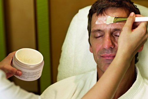 Ein Mann erhält eine entspannende Gesichtsbehandlung im SPA-ROSA, während er auf einer Massageliege liegt.